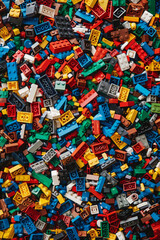 A chaotic yet colorful jumble of toy bricks, tightly packed to fill the entire frame. The bricks come in various sizes and an array of colors including red, blue, green, yellow, and white,