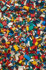 Naklejka premium A chaotic yet colorful jumble of toy bricks, tightly packed to fill the entire frame. The bricks come in various sizes and an array of colors including red, blue, green, yellow, and white,