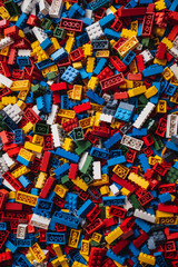 A chaotic yet colorful jumble of toy bricks, tightly packed to fill the entire frame. The bricks come in various sizes and an array of colors including red, blue, green, yellow, and white,