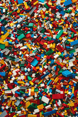 A chaotic yet colorful jumble of toy bricks, tightly packed to fill the entire frame. The bricks come in various sizes and an array of colors including red, blue, green, yellow, and white,