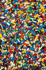 Fototapeta premium A chaotic yet colorful jumble of toy bricks, tightly packed to fill the entire frame. The bricks come in various sizes and an array of colors including red, blue, green, yellow, and white,
