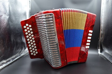 A vibrant red Colombian vallenato accordion featuring the colors of the Colombian flag (red,...