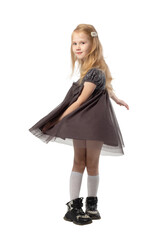 A little blonde girl in a dress poses in the studio isolated on a white background.