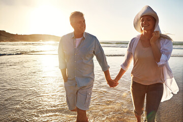 Senior, happy couple and holding hands with relax on beach sunset for support, love or bonding in nature. Man, woman or lovers walking with smile on outdoor summer holiday by water or ocean coast - Powered by Adobe