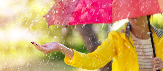 Woman standing outdoors with umbrella under the spring rain.