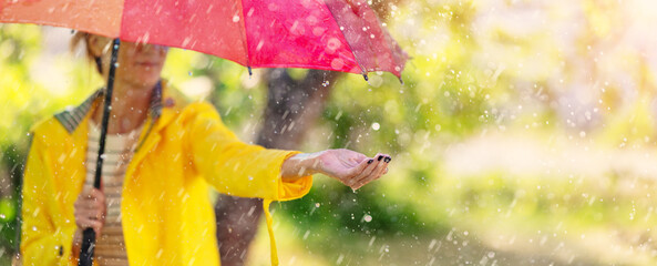 Woman standing outdoors with umbrella under the spring rain.
