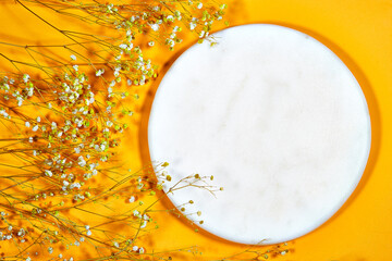 Top view of empty marble podium and yellow gypsophila flowers. Pedestal and fresh natural leaf for cosmetic advertising. Eco product presentation mockup. flat lay