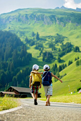 Obraz premium Two little children, boy brothers with backpacks travel on the road to scenic mountains