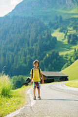 Cute little child with backpacks travel on the road to scenic mountains