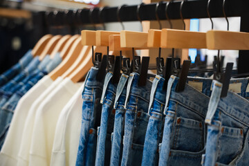 Jeans on the hanger in the store. Clothes on hangers in shop for sale. Blur background. Fashionable...