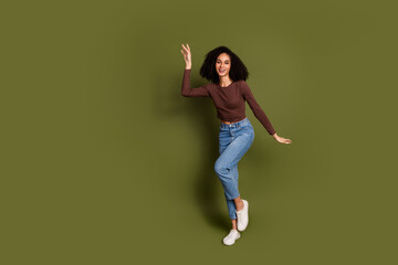 Full size photo of pretty young girl dancing have fun wear trendy brown outfit isolated on khaki...