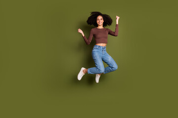 Full body photo of attractive young woman jump winning raise fists dressed stylish brown clothes...
