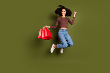 Full size photo of pretty young girl jump winning shopping bags wear trendy brown outfit isolated...