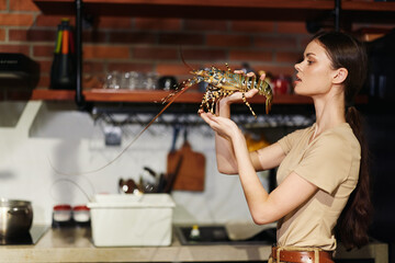 Woman holding a lobster in front of kitchen counter, preparing fresh seafood for a meal