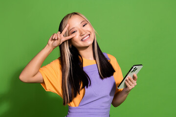 Photo portrait of pretty young girl hold device show v-sign wear trendy violet yellow outfit...