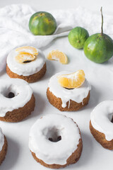 Iced mini bundt cake on a white tray, vanilla bundlette cakeswith a clementine segment on a white background, small vanilla bundt cakes with an icing glaze