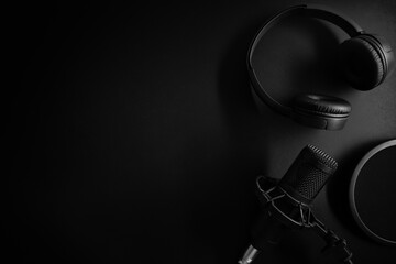 studio microphone and headphones on black background with copy space. sound recording equipment. top view