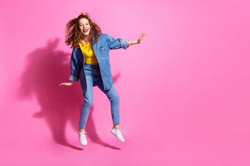 Full length photo of adorable lovely girl wear jeans shirt jumping high empty space isolated pink...