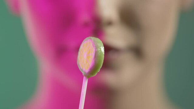 Kobieta apetycznie oblizuje lizak owocowy