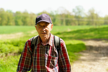 Portrait of senior man with backpack in the forest on a sunny day