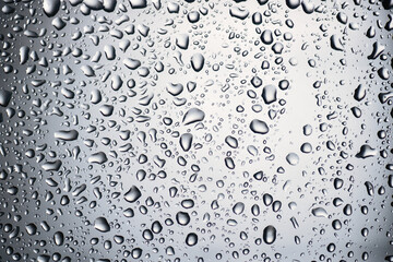Close-Up of Water Droplets on Glass Surface Creating Abstract Pattern with Reflections and Light...
