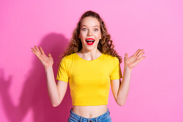 Photo of adorable excited girl wear yellow crop top rising arms empty space isolated pink color...