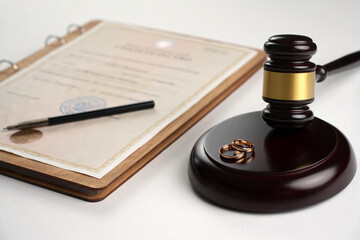 Marriage contract, golden wedding rings and gavel on white background, close-up