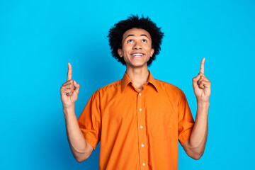 Photo of handsome dreamy guy wear orange shirt looking showing two fingers up emtpy space isolated...
