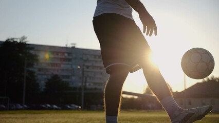 Legs of young man kicking ball at green field. Male feet of professional footballer juggling soccer...