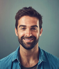 Obraz premium Happy man, fashion and style in portrait, trendy and cheerful with gray background in studio. Male person, smile and outfit for confidence, retail or sale in advertisement or promotion in denim shirt