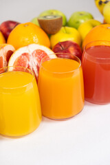 Different fruit juices in glasses on white background