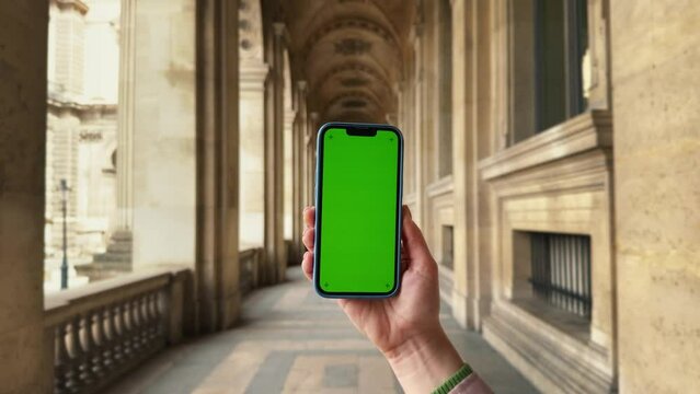 Close-up shot of hand using mobile phone with green screen mock up at the museum. Chroma key.