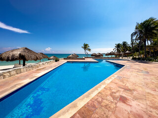 Panoramic view of a beautiful pool of a luxurious white sandy beach resort, with the turquoise and crystal clear sea of the Caribbean Sea in Mexico.
