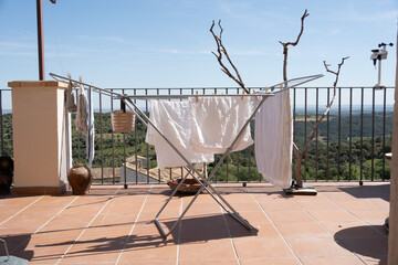 Photograph of washing clothes, sheets and towels on a clothesline on a terrace, in the background...