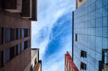 Obraz premium office building opposite of an old building with a cloudy sky