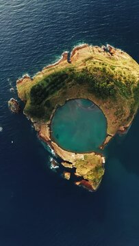 Vertical Screen: Breathtaking aerial view of an islet in the Azores, Portugal, surrounded by lush greenery, tranquil lagoon, and expansive ocean, showcasing the beauty of the natural world