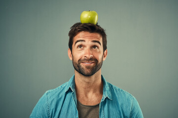 Man, diet and balance apple on head for healthy nutrition, wellness and natural organic food...