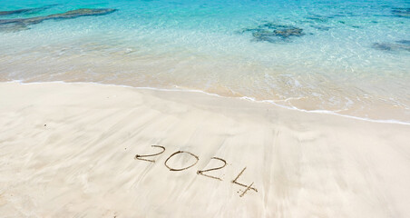 The year 2024 written in the sand at the beach