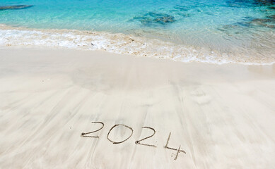 The year 2024 written in the sand at the beach