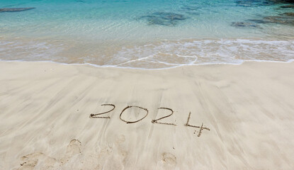 The year 2024 written in the sand at the beach