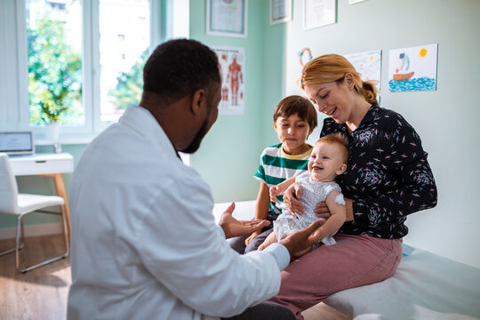 Pediatrician interacting with young family during checkup in clinic