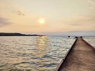 Obraz premium Sunset over a wooden pier by the sea with reflections on the water in Koh Kood, Trat, Thailand