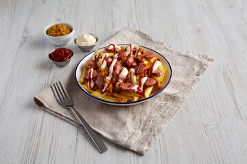 Homemade Salchipapa Fries with Ketchup, Mustard and Mayo on a Plate, side view.