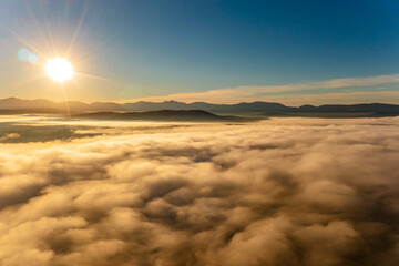 Fototapeta premium Drone flies over fluffy clouds before sunset. Photo above clouds, sense of wonder and admiration.