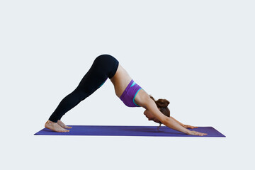 Beautiful young fitness woman in fashion sports clothes doing warm-up and exercises on a mat on an isolated light background