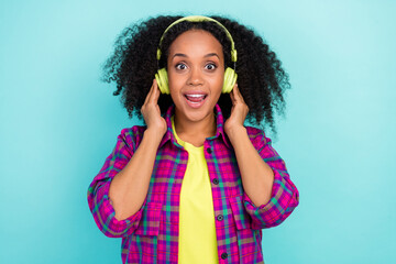 Photo of pretty young woman touch headphones wear checkered shirt isolated on teal color background