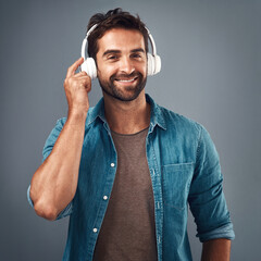 Portrait, man and headphone for music in studio, audio media and podcast or ebook on gray...