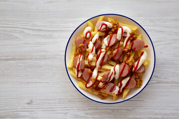 Homemade Salchipapa Fries with Ketchup, Mustard and Mayo on a Plate, top view. Copy space.
