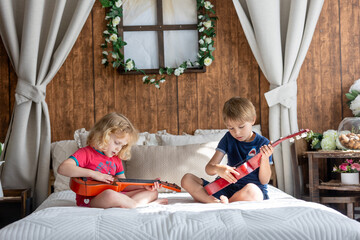 Cute sweet toddler children, tickling feet on the bed, laughing and smiling