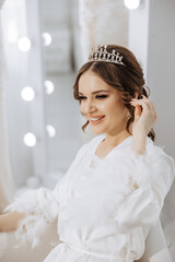 A woman is sitting in a chair with a tiara on her head. She is smiling and she is happy